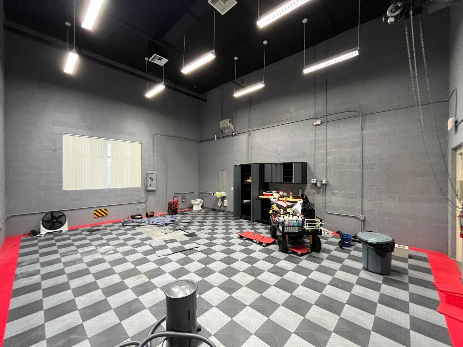 Finished shop with grey and white checkered interlocking floor tiles, red border and black ceiling with linear lights